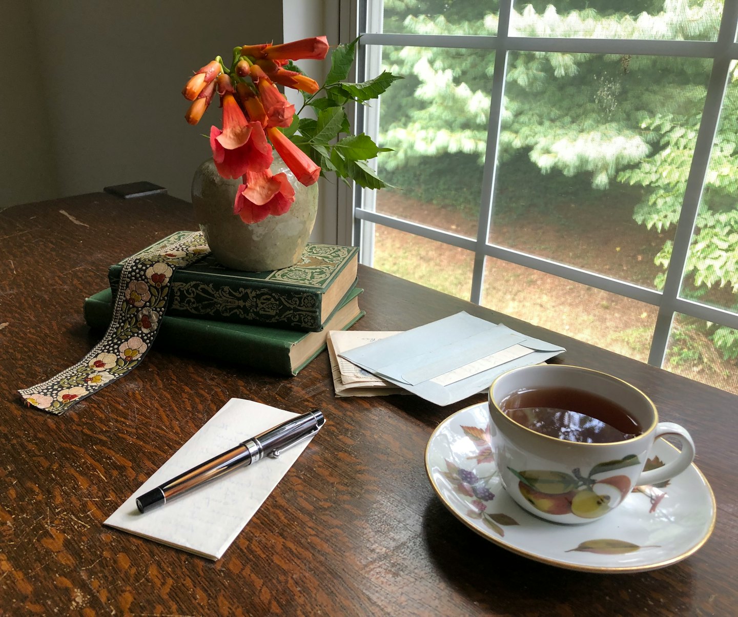 Desk with books, flowers, and a fountain pen.
